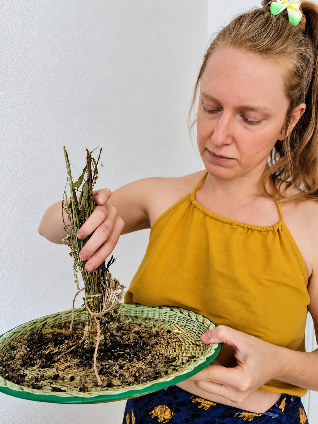Adriana Sroczyńska-Andruszewska z pękiem suszonych ziół nad plecionym koszem